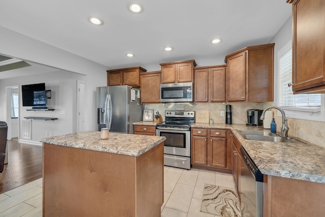 kitchen with stainless steel appliances, sink, tasteful backsplash, a kitchen island, and light wood-type flooring