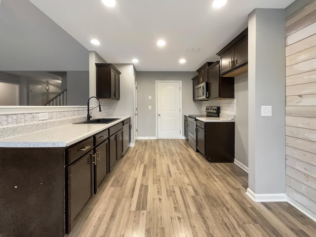 kitchen with dark brown cabinets, sink, light wood-type flooring, and appliances with stainless steel finishes