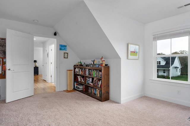 additional living space with light colored carpet and vaulted ceiling