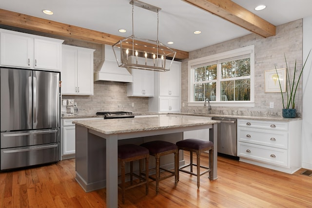 kitchen featuring light wood-type flooring, white cabinetry, a center island, and stainless steel appliances