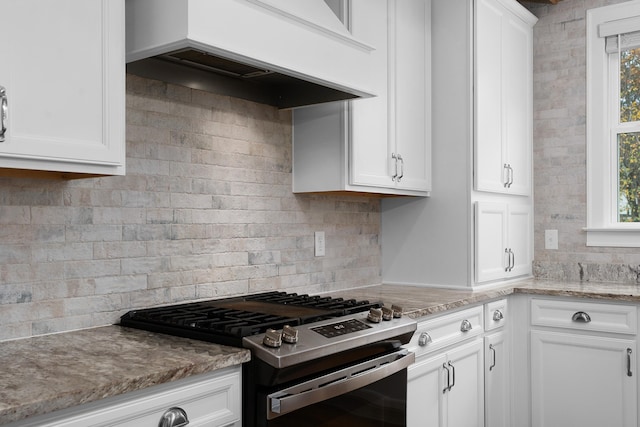 kitchen with a wealth of natural light, white cabinetry, backsplash, and gas stove