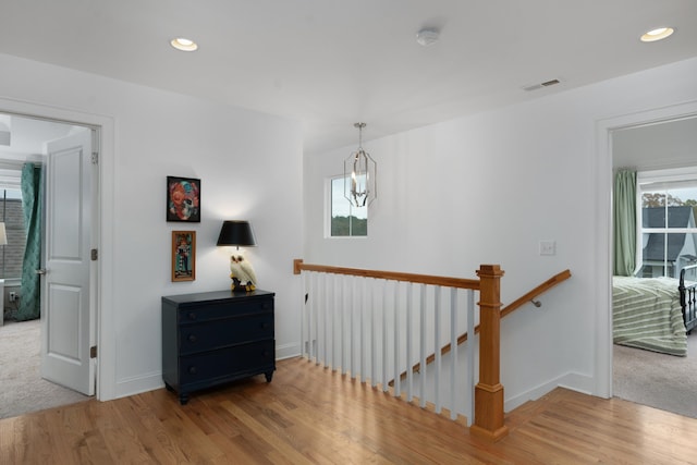 hall with hardwood / wood-style flooring and a notable chandelier