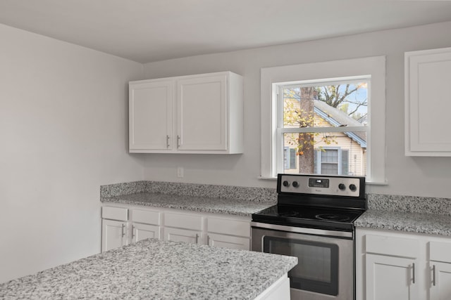 kitchen with white cabinetry, light stone countertops, and stainless steel electric stove