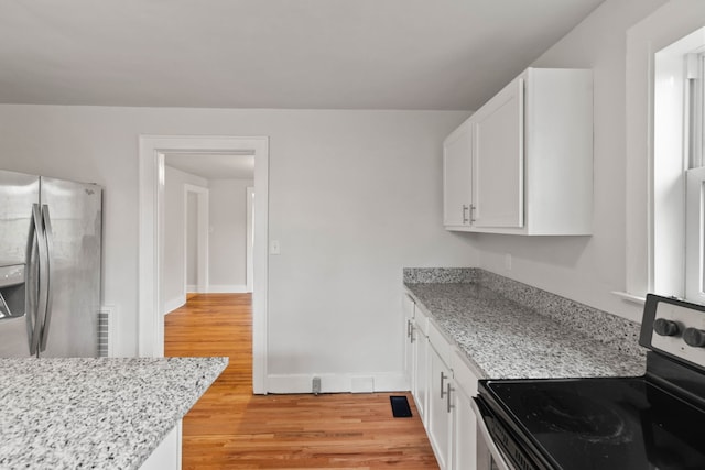 kitchen featuring light stone countertops, range with electric cooktop, light hardwood / wood-style flooring, white cabinets, and stainless steel fridge with ice dispenser