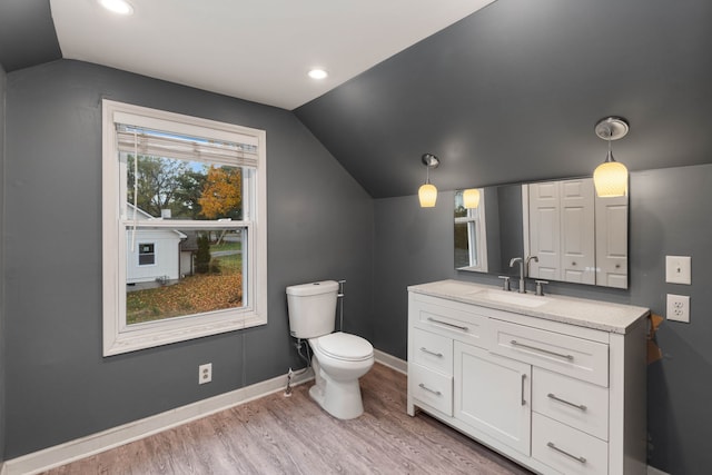 bathroom with toilet, vanity, lofted ceiling, and hardwood / wood-style floors