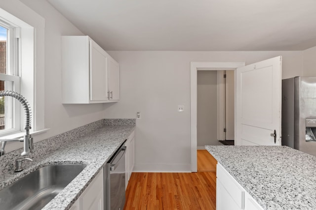 kitchen featuring light stone counters, stainless steel appliances, sink, light hardwood / wood-style floors, and white cabinets