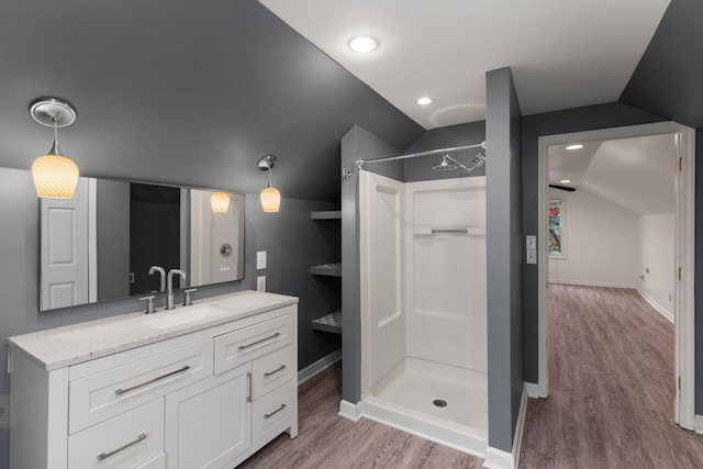 bathroom featuring wood-type flooring, vanity, vaulted ceiling, and a shower