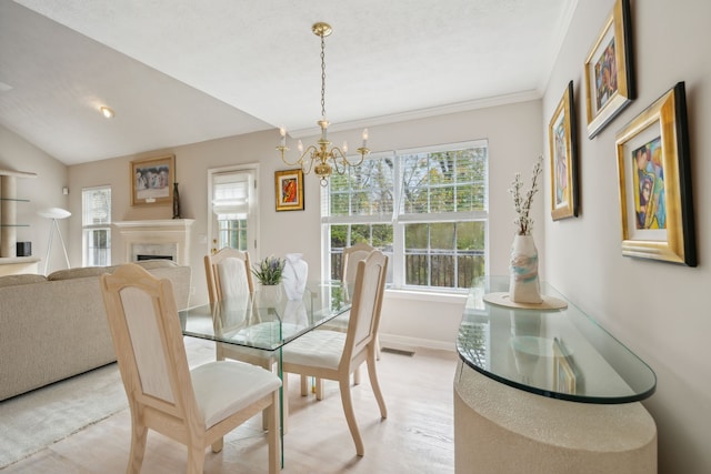 dining area featuring plenty of natural light, vaulted ceiling, ornamental molding, and an inviting chandelier