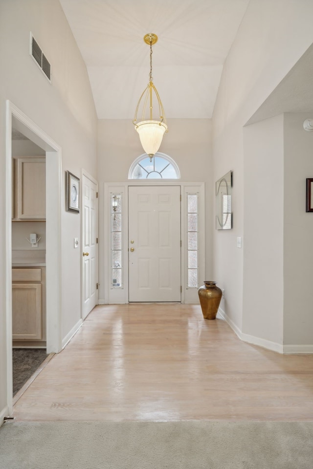 foyer entrance featuring light colored carpet and vaulted ceiling