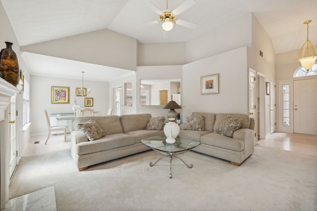 carpeted living room with high vaulted ceiling and ceiling fan with notable chandelier