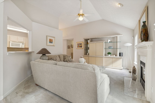 carpeted living room featuring a high end fireplace, vaulted ceiling, and ceiling fan