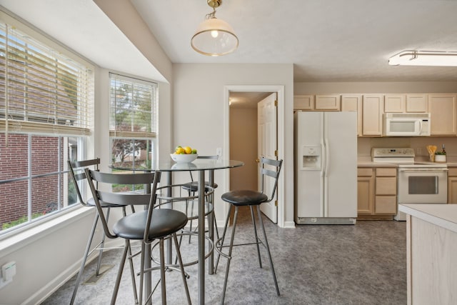 kitchen with decorative light fixtures, white appliances, and light brown cabinetry