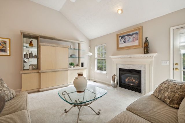 living room with a high end fireplace, light colored carpet, and vaulted ceiling