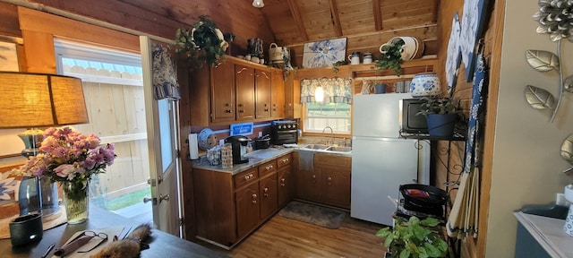 kitchen featuring lofted ceiling with beams, white fridge, light wood-type flooring, sink, and wooden ceiling