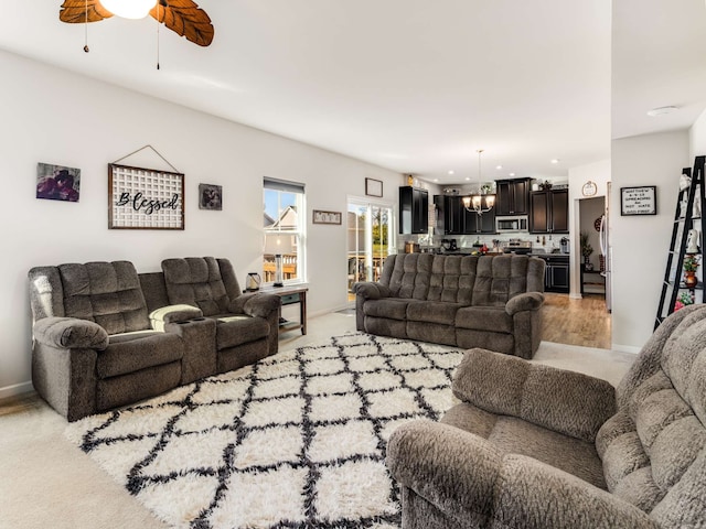 living room with ceiling fan with notable chandelier and light colored carpet