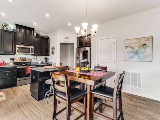 kitchen featuring stainless steel appliances, hanging light fixtures, light wood-type flooring, and tasteful backsplash