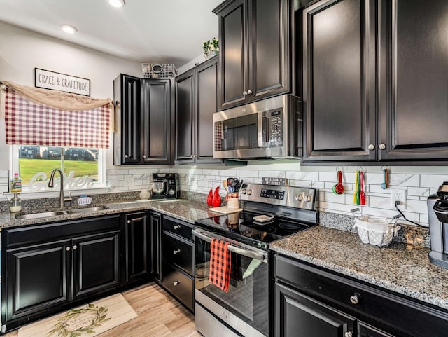 kitchen featuring dark stone counters, decorative backsplash, light hardwood / wood-style flooring, sink, and appliances with stainless steel finishes