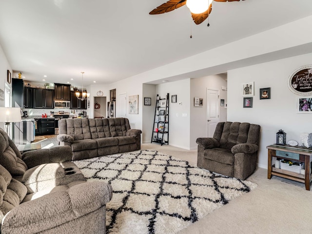 carpeted living room with ceiling fan with notable chandelier