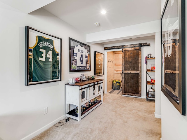 corridor featuring light carpet and a barn door