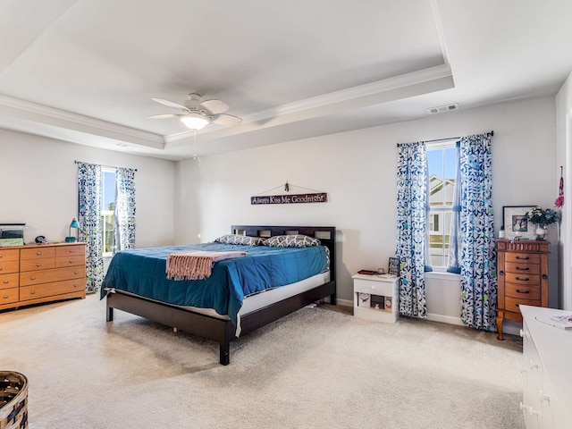 carpeted bedroom with multiple windows, crown molding, ceiling fan, and a raised ceiling