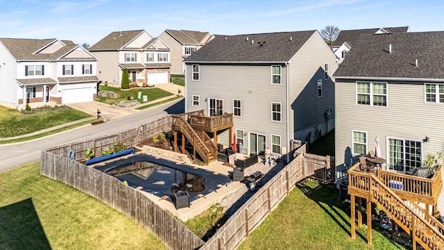 rear view of property featuring a deck, a garage, a yard, and a patio area