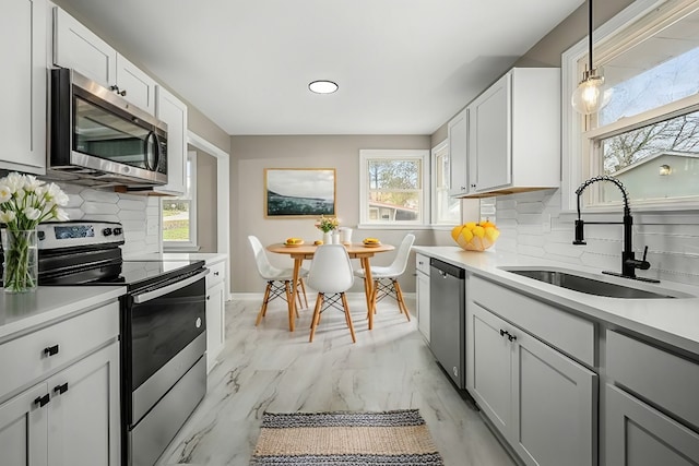 kitchen with decorative backsplash, hanging light fixtures, sink, and stainless steel appliances