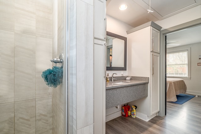 bathroom with hardwood / wood-style floors, a shower with door, and sink