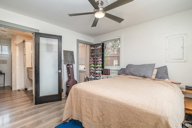 bedroom with electric panel, ceiling fan, and light hardwood / wood-style flooring