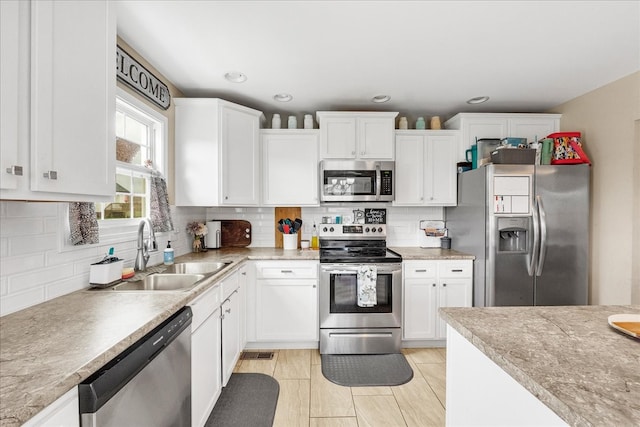 kitchen featuring tasteful backsplash, white cabinetry, appliances with stainless steel finishes, and sink