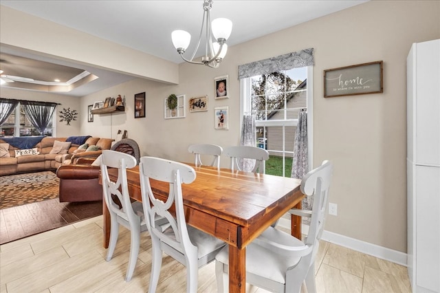 dining space with ceiling fan with notable chandelier and light wood-type flooring