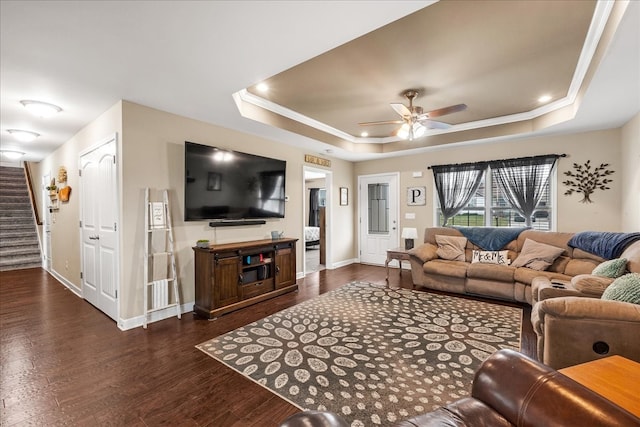 living room with crown molding, dark hardwood / wood-style flooring, ceiling fan, and a raised ceiling