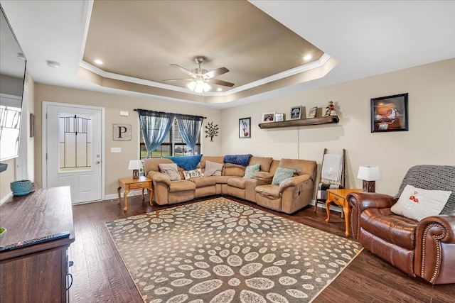 living room featuring ceiling fan, a tray ceiling, and dark hardwood / wood-style floors