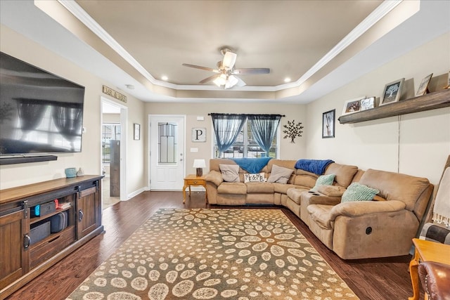 living room featuring ornamental molding, dark wood-type flooring, ceiling fan, and a tray ceiling