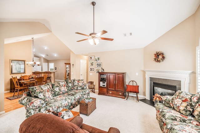 living room with ceiling fan with notable chandelier, light carpet, and vaulted ceiling