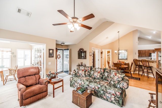 living room with high vaulted ceiling, light wood-type flooring, and ceiling fan with notable chandelier