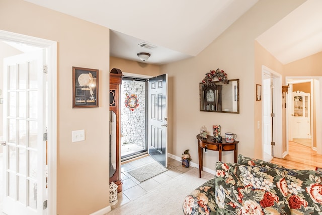 entrance foyer with light tile patterned flooring and vaulted ceiling