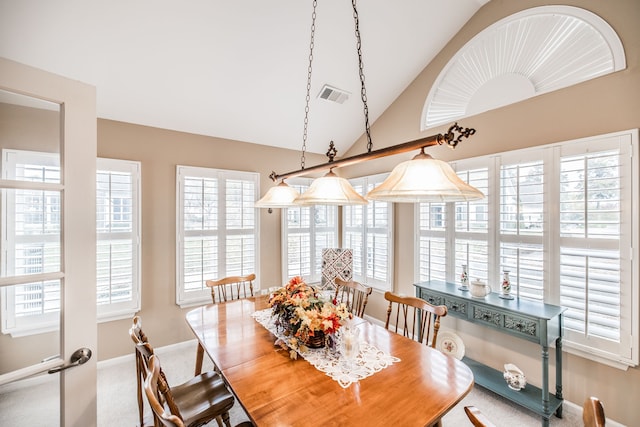 carpeted dining room with a wealth of natural light and lofted ceiling