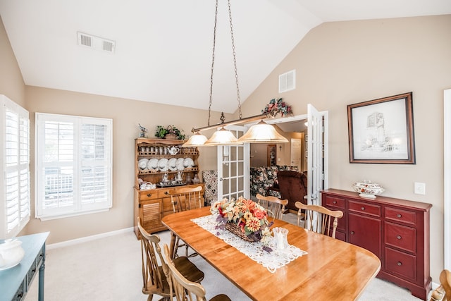 carpeted dining room with vaulted ceiling