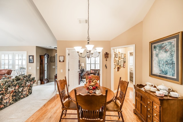 dining room with an inviting chandelier, a healthy amount of sunlight, light hardwood / wood-style flooring, and high vaulted ceiling