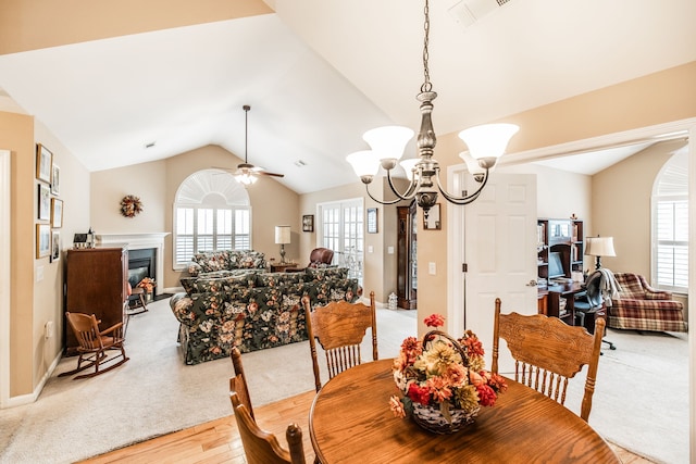 dining space featuring ceiling fan with notable chandelier, light hardwood / wood-style flooring, and lofted ceiling