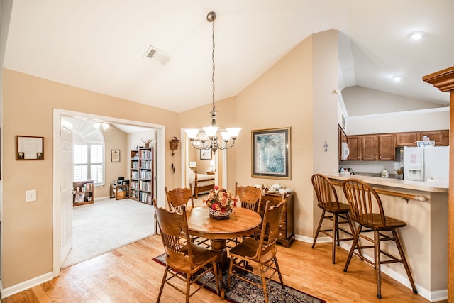 dining area featuring a chandelier, vaulted ceiling, and light hardwood / wood-style floors