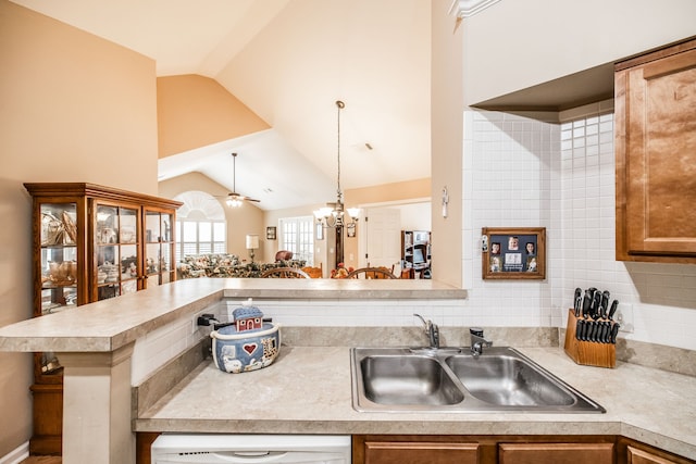 kitchen with white dishwasher, high vaulted ceiling, sink, kitchen peninsula, and ceiling fan with notable chandelier