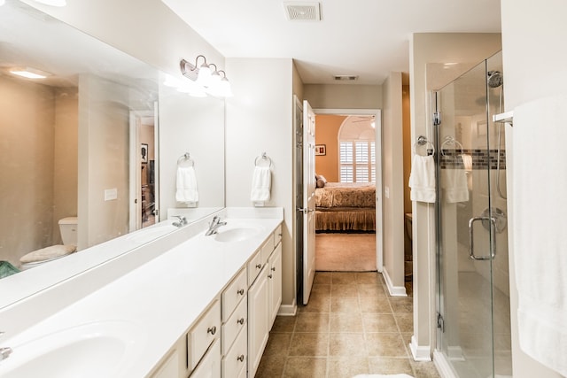 bathroom featuring toilet, vanity, tile patterned flooring, and a shower with door