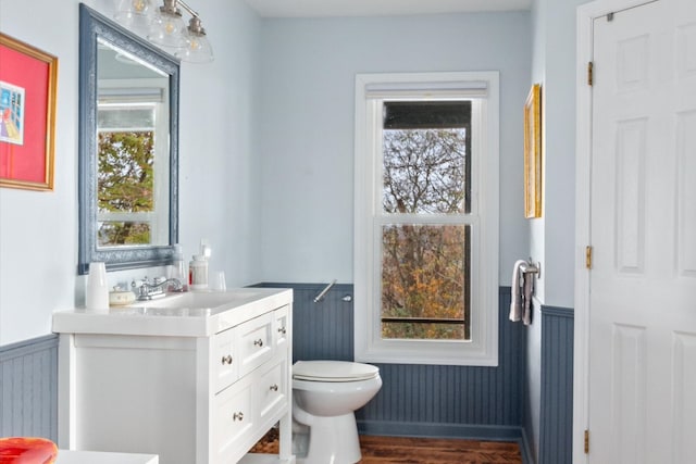 bathroom with toilet, vanity, a wealth of natural light, and hardwood / wood-style flooring