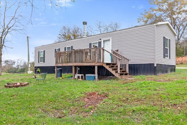 back of property with a lawn, an outdoor fire pit, and a wooden deck