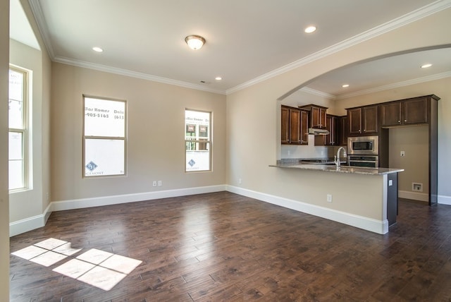 kitchen with light stone counters, dark hardwood / wood-style floors, crown molding, dark brown cabinets, and appliances with stainless steel finishes