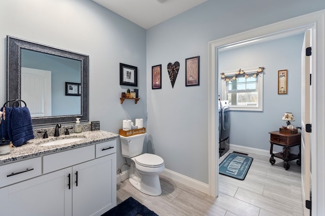 bathroom with hardwood / wood-style floors, washer / dryer, vanity, and toilet