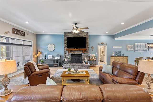 living room featuring a fireplace, ceiling fan with notable chandelier, light hardwood / wood-style floors, and crown molding