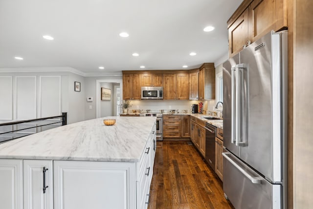 kitchen with dark wood-type flooring, white cabinets, light stone counters, a kitchen island, and appliances with stainless steel finishes