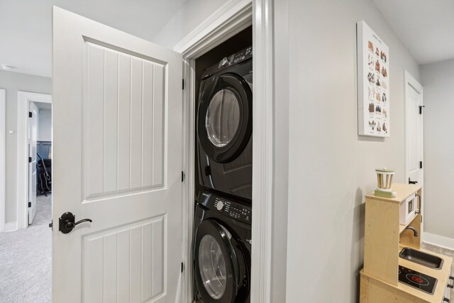 clothes washing area with carpet and stacked washer and clothes dryer